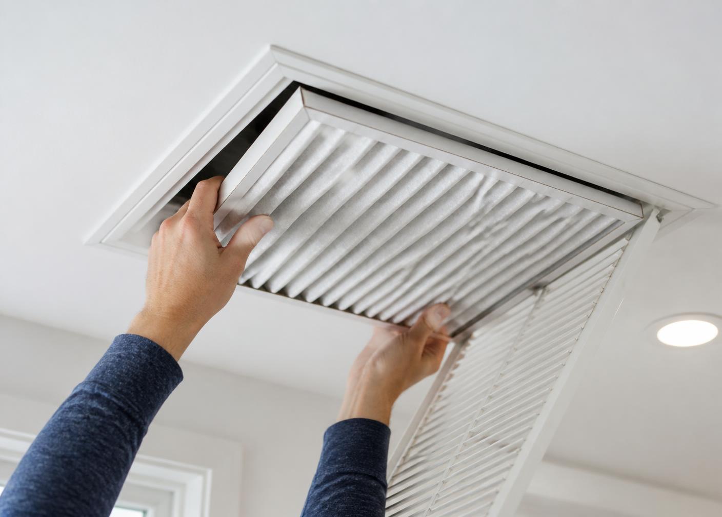 Homeowner replacing a pleated air filter in a ceiling return vent
